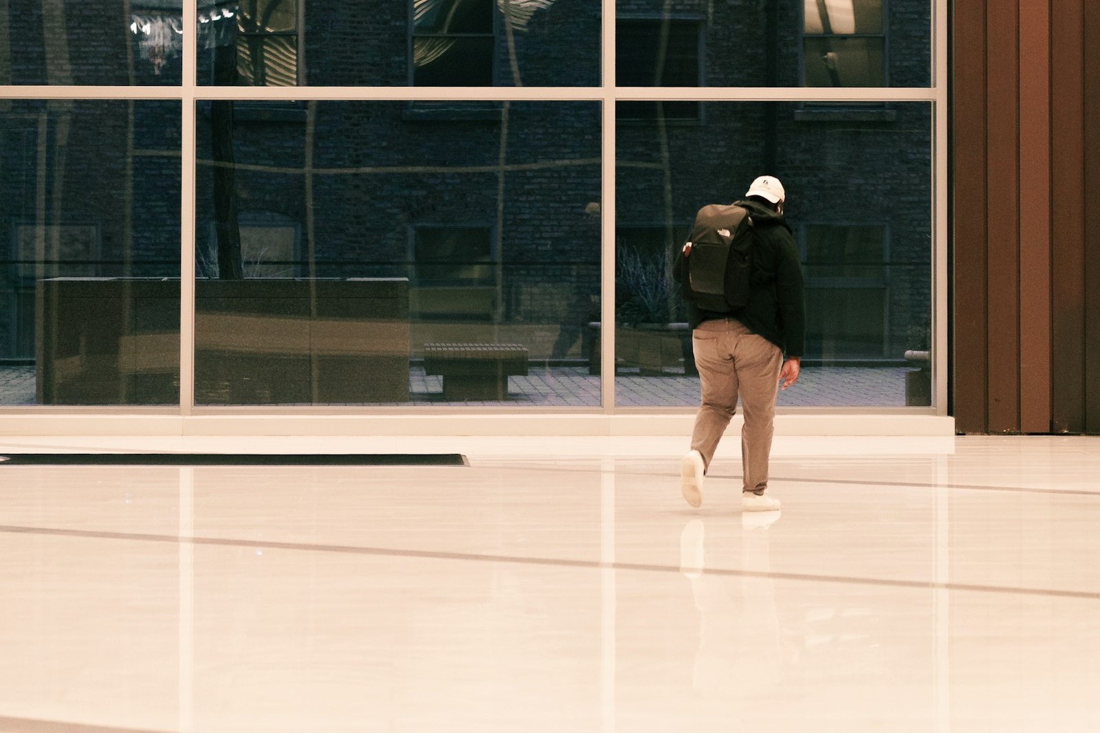 A person walking through a quiet office lobby, seen from behind