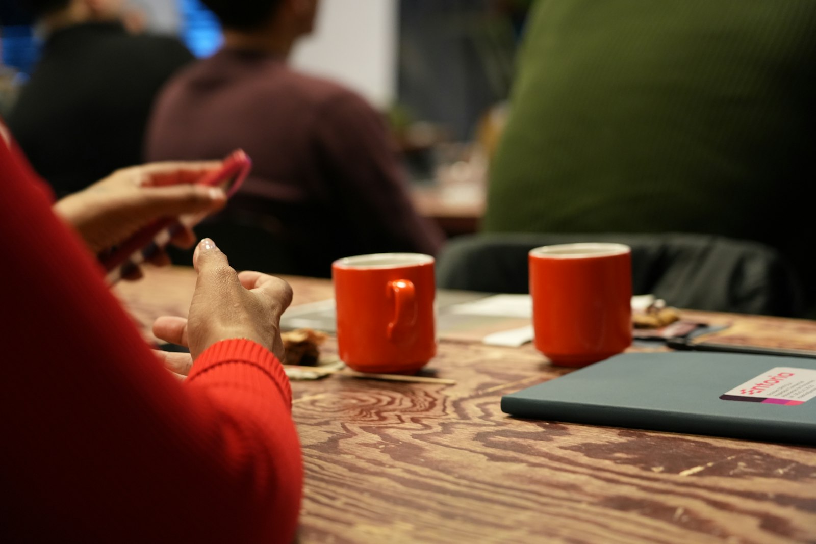 Two people talking across a table, cups between them, hands mid-gesture
